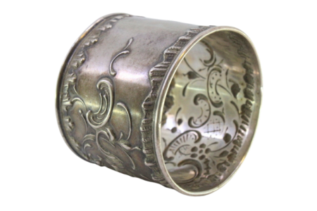 Argola de guardanapo em prata com volutas relevadas envolvendo cartela para monograma.